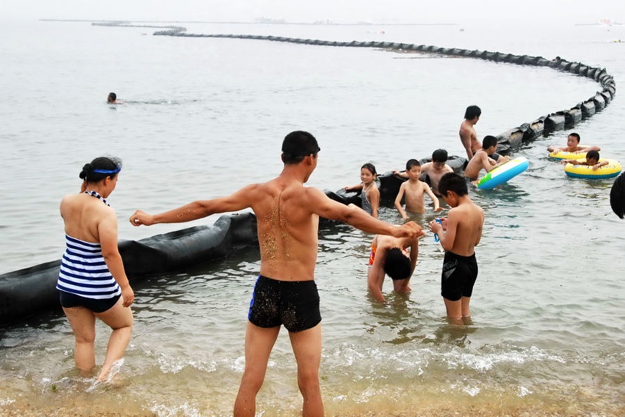 7月24日，大连付家庄海滨浴场，游客在隔油带旁消暑纳凉-2.jpg